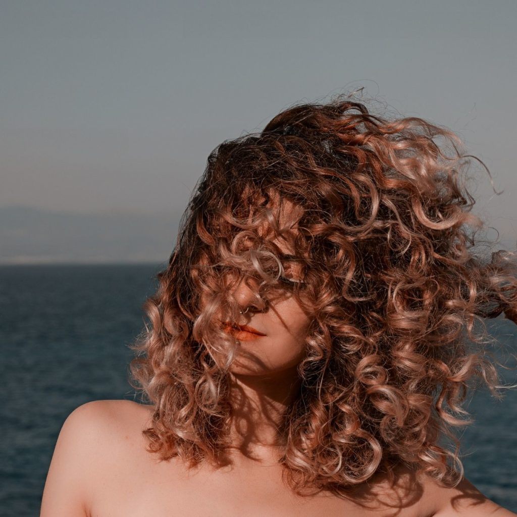 woman with curly hair covering face